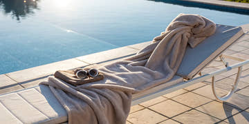 A fleece-lined swim parka on a lounge chair next to a swimming pool.