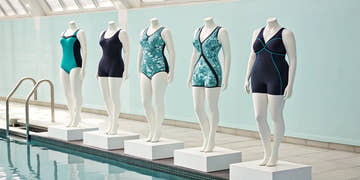 Various styles of chlorine resistant plus size swimsuits on mannequins by a pool.