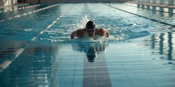 A serious swimmer racing in a pool wearing high-performance swimwear.