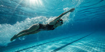 A swimmer achieves peak performance in a black training swimming suit.