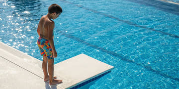 Young boy wearing a colorful boys swim suit at the pool.