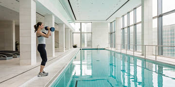Woman performing exercises with water dumbbells in an indoor pool.