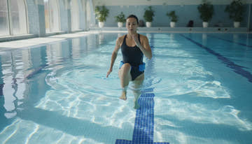 Swimmer aqua jogging with a flotation belt in an indoor pool