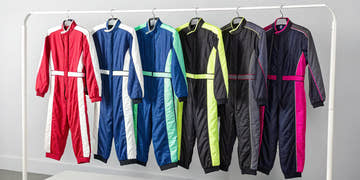 A selection of girls' racing suits in various styles and colors hanging on a rack.