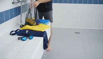 Swim gear including goggles, swimsuit, fins, and kickboard neatly arranged on a bench in a bright locker room