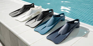 Different types of swim fins in various colors ready for a training session at the pool.