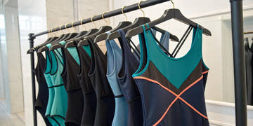 Various styles of chlorine resistant swimsuits for women displayed on a clothing rack.