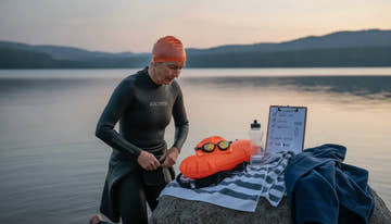 Open water swimmer preparing swim gear beside a lake
