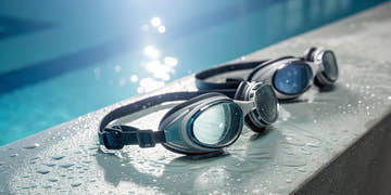 A pair of smart swim goggles on a pool deck, ready to track real-time performance metrics.