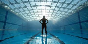 A swimmer in racing swimwear focuses before a competition at the pool.