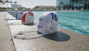 Water polo caps with protective ear guards beside a pool