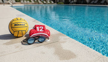 Water polo ball and cap next to pool deck