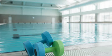 Foam aquatic dumbbells beside a clear swimming pool
