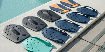 A variety of swim paddles in different shapes and colors for a swimmer to choose the best pair.